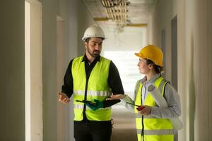 ingenieur en architect werken Aan de bouw plaats, dubbel checken plannen en werkwijze. foto