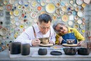 in de pottenbakkerij werkplaats, een Aziatisch gepensioneerd paar is verloofd in pottenbakkerij maken en klei schilderij activiteiten. foto