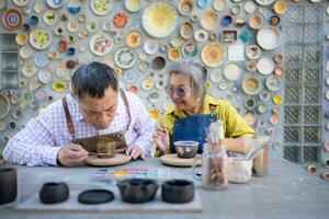 in de pottenbakkerij werkplaats, een Aziatisch gepensioneerd paar is verloofd in pottenbakkerij maken en klei schilderij activiteiten. foto