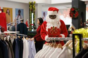 op te slaan arbeider tekening winnaar naam Bij verloten wedstrijd met ongeduldig klanten, aanbieden Kerstmis prijs naar Lucky persoon Bij boodschappen doen winkelcentrum. jong volwassen in de kerstman claus pak draag- doos. foto