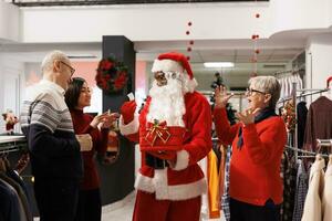 jong Mens presenteren wedstrijd winnaars in kleding op te slaan, lezing namen van deelnemers van papieren. Afrikaanse Amerikaans persoon in de kerstman claus kostuum groet mensen Bij prijs tekening verloten. foto