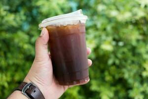 hand- Holding een nemen weg plastic kop van bevroren zwart koffie foto