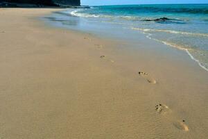 voetafdrukken in de zand Aan een strand in de buurt de oceaan foto