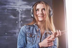 mode, kleding, mensen concept. close-up aantrekkelijke sexy jonge vrouw met jeans jasje. meisje poseert in de studio luistert naar muziek in een koptelefoon