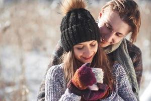 foto van gelukkige man en mooie vrouw met kopjes buiten in de winter. wintervakantie en vakantie. kerst paar gelukkige man en vrouw drinken warme wijn. verliefd stel