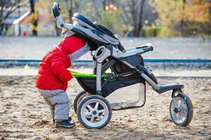 een klein kind duurt zijn speelgoed uit van de wandelwagen foto