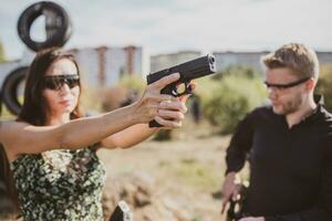 een wapens instructeur geeft les een meisje naar schieten een pistool Bij een schieten reeks foto