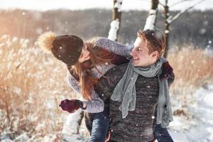 paar heeft plezier en lacht. kus. jonge hipster paar knuffelen elkaar in winter park. winter liefdesverhaal, een mooi stijlvol jong stel. wintermodeconcept met vriend en vriendin foto