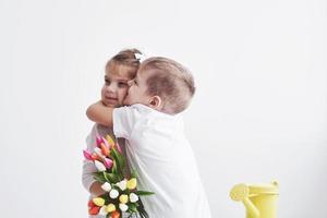 mooie jongen en meisje met tulpen met omhelzing. moederdag, 8 maart, een gelukkige verjaardag foto