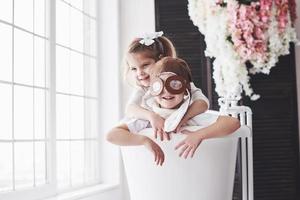 portret van een meisje en een jongen in pilotenhoed die in de badkamer spelen bij piloten of matrozen. het concept van reizen, kindertijd en de realisatie van dromen foto