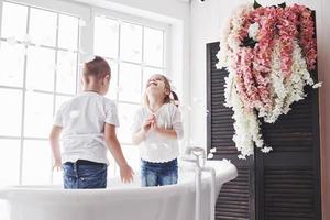 kind spelen met rozenblaadjes in huis badkamer. klein meisje en jongen samen plezier en vreugde. het concept van de kindertijd en de realisatie van dromen, fantasie, verbeelding foto