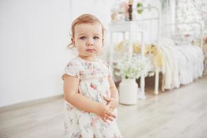 mooi klein meisje dat speelgoed speelt. blondine met blauwe ogen. witte stoel. kinderkamer. gelukkig klein meisjesportret. kindertijd concept foto