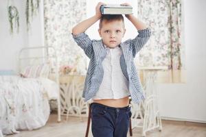 foto van ijverige schooljongen met boek op zijn hoofd huiswerk maken. de schooljongen is het huiswerk beu