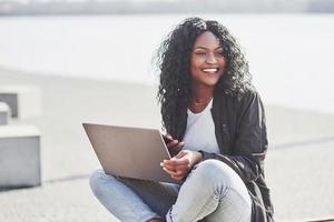 jonge vrouw op straat die aan laptop werkt en op mobiele telefoon praat foto