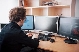 mannelijke programmeur werkt op desktopcomputer met veel monitoren op kantoor in softwareontwikkelingsbedrijf. programmeer- en coderingstechnologieën voor websiteontwerp foto