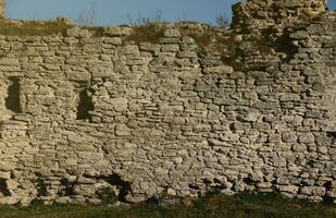 heel oud steen steen muur van kasteel of vesting van 18e eeuw. vol kader muur met verouderd vuil en gebarsten bakstenen foto