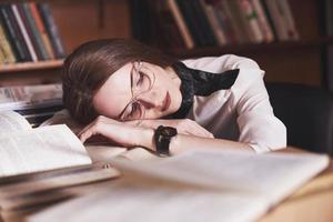een jonge studente is moe in de leeszaal van de oude bibliotheek foto