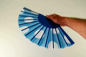een persoon Holding een blauw en wit polka punt ventilator foto
