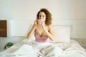vrouw in nachtkleding drinken vers koffie in bed foto