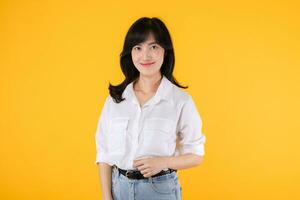 mooi zakenvrouw. Aziatisch vrouw ondernemer gelukkig glimlach vervelend wit overhemd en denim planten met zelfverzekerd en slim op zoek isolatie Aan geel achtergrond. reclame Product en onderhoud concept. foto