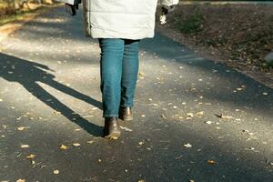 vrouw in elegant herfst kleding genieten van een vredig wandeling Aan een zonnig vallen dag foto