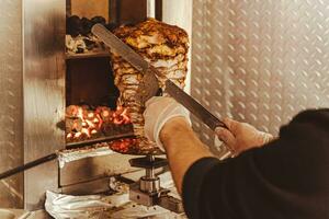 chef snijden vlees van vleespen voor Koken shoarma - populair snel voedsel lekkernij foto