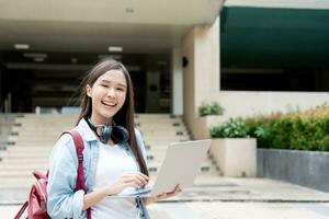 mooi Aziatisch vrouw vrouw leerling opgewonden controle taal test resultaten Aan laptop. glimlach meisje gelukkig studie online. boek in college campus. portret vrouw Aan Internationale Azië Universiteit foto