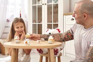 aanbiddelijk dochter vervelend een wit jurk waarmee haar liefhebbend vader. ze zijn drinken thee van een speelgoed- gerechten in een modern kinderen kamer. gelukkig familie. foto