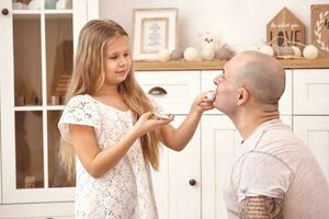 aanbiddelijk dochter vervelend een wit jurk waarmee haar liefhebbend vader. ze zijn drinken thee van een speelgoed- gerechten in een modern kinderen kamer. gelukkig familie. foto