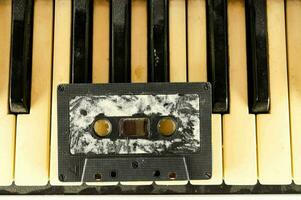 een oud cassette is zittend Aan top van piano sleutels foto