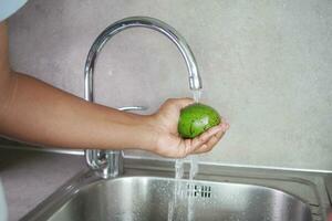 hand- het wassen avocado met water sprenkeling foto