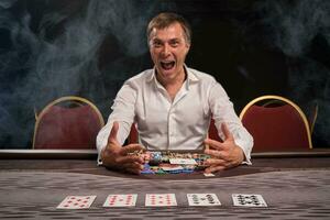 knap emotioneel Mens is spelen poker zittend Bij de tafel in casino. foto