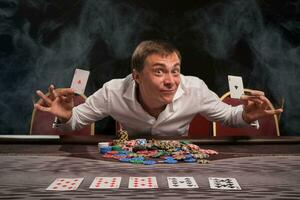 knap emotioneel Mens is spelen poker zittend Bij de tafel in casino. foto