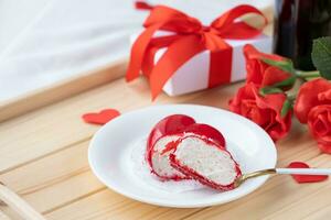 hart vormig geglazuurd Valentijn taart en bloemen Aan houten dienblad foto
