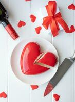 hart vormig geglazuurd Valentijn taart en bloemen Aan houten tafel foto