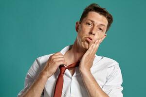 portret van een jong brunet Mens poseren in een studio tegen een blauw achtergrond. foto