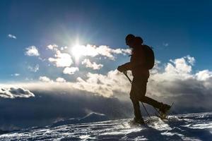 man loopt in de sneeuw met sneeuwschoenen foto