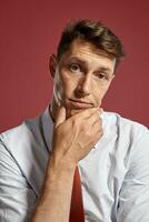 portret van een jong brunet Mens poseren in een studio tegen een rood achtergrond. foto