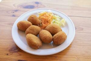 een bord van ham kroketten, Aan een houten tafel. de meest geliefde kroketten in Spanje. foto