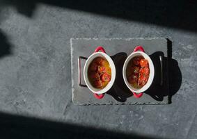 gebakken kers tomaten in geportioneerd pannen onder zonlicht Aan de tafel, plat leggen, moeilijk licht, ingrediënt voor caprese smakelijk foto