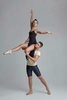 twee atletisch modern ballet dansers zijn poseren tegen een grijs studio achtergrond. foto