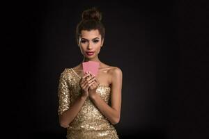 vrouw winnend - jong vrouw in een classy goud jurk Holding twee kaarten, een poker van azen kaart combinatie. emoties foto