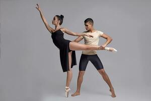 twee atletisch modern ballet dansers zijn poseren tegen een grijs studio achtergrond. foto