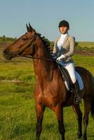 jong vrouw rijden een paard Aan de groen veld- foto