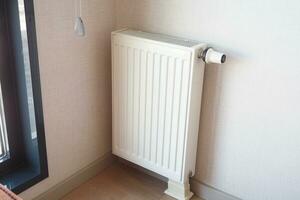 wit radiator Aan grijs wit muur. appartement verwarming installatie systeem, foto