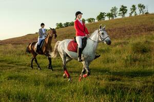 te paard ruiters. twee aantrekkelijk Dames rijden paarden Aan een groen weide foto