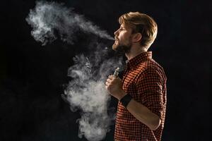 een jong Mens met een baard en een elegant kapsel in een shirt, roken een sigaret, een adder, een kamer, een studio, rook, genot foto