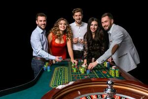 groep van jong mensen achter roulette tafel in een casino foto