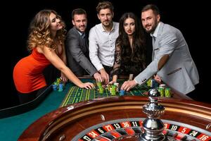 groep van jong mensen achter roulette tafel in een casino foto