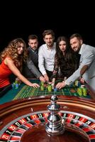 groep van jong mensen achter roulette tafel in een casino foto